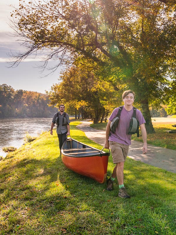 students carrying kayak by the river